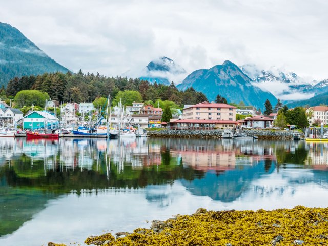Buildings and boats in harbor of Sitka, Alaska, framed by mountains