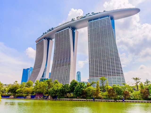 A picture of three tall buildings linked together by a long, oval-shaped roof