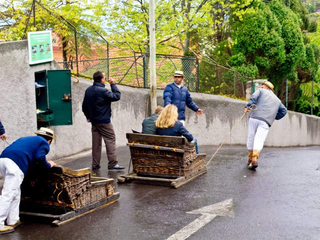 People riding toboggan pulled by operator in Madeira, Portugal