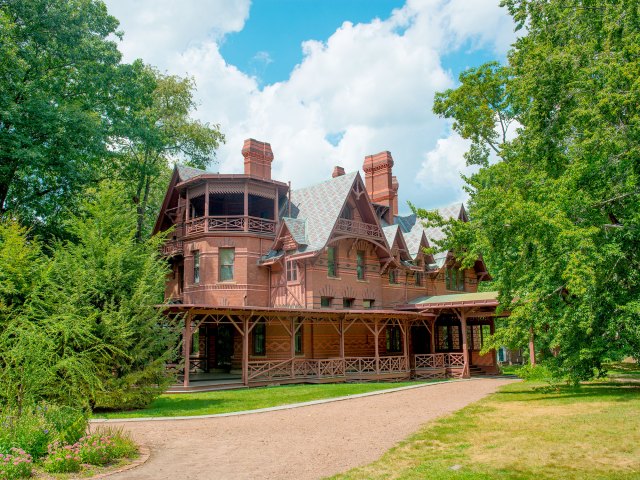 An old red stone house surrounded by green trees