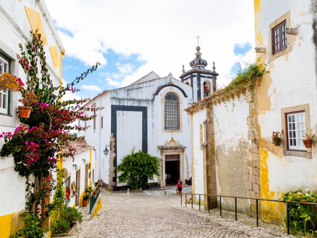 A picture of a white church colonial style surrounded by white and yellow buildings