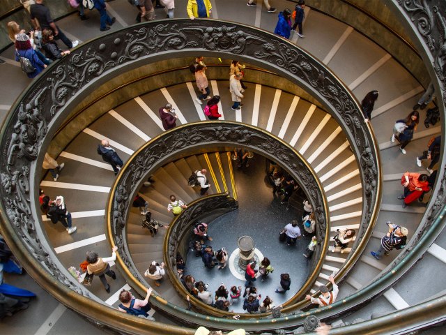 People walking on spiraling Bramante Staircase, looking down from the top