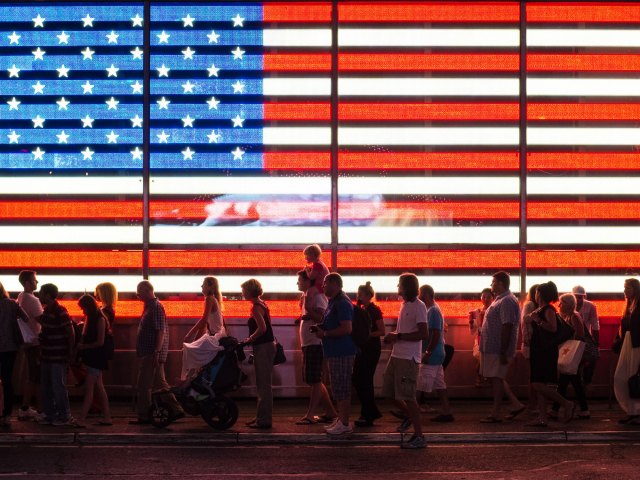 People standing in line in front of neon-lit American flag