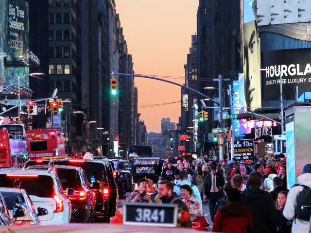 People and cars fill busy New York City street at sunset
