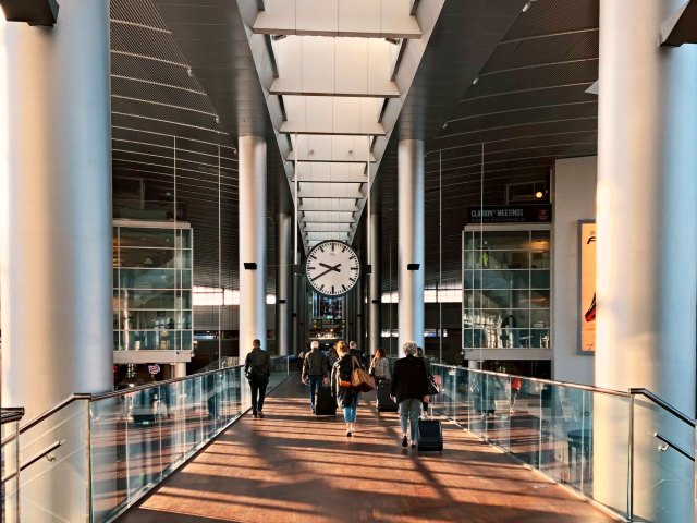 Passengers walking under giant clock in airport terminal