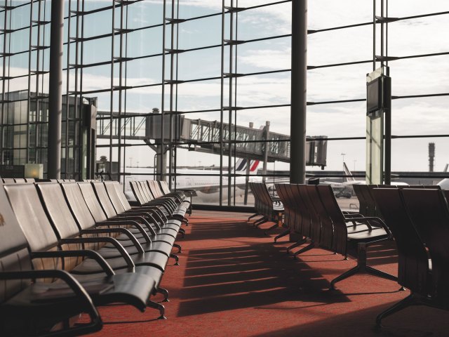 Empty seating area at airport gate with view of airplanes on tarmac