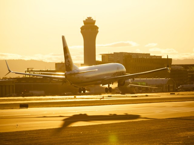 Airplane landing on runway at sunset
