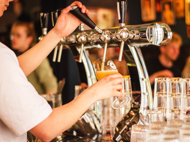 Bartender filling beer glass from keg