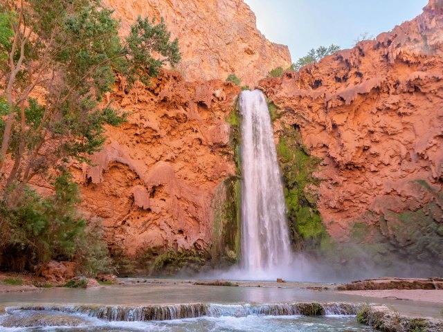 A picture of the tall Supai Falls against red rocks