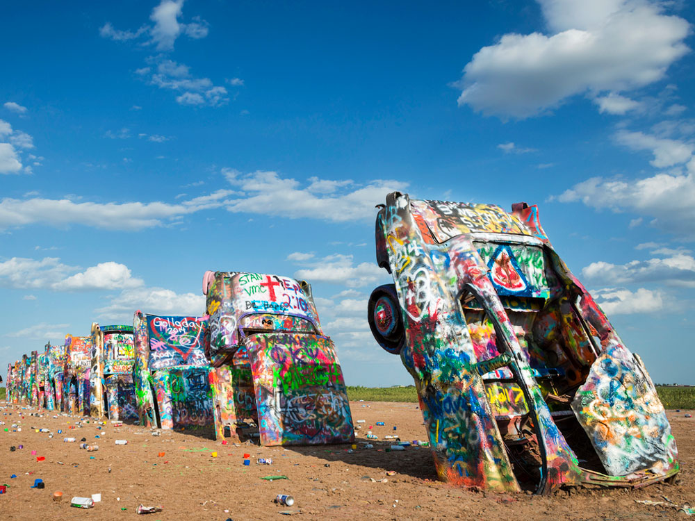 Graffiti-covered cars partially buried in desert at Cadillac Ranch in Texas