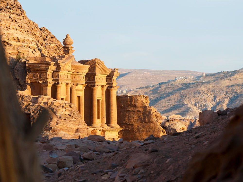 Buildings carved out of rock facade overlooking desert valley in Petra, Jordan