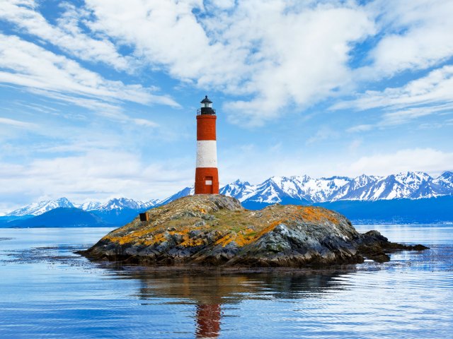 Red-and-white lighthouse on small rocky island in Ushuaia, Argentina