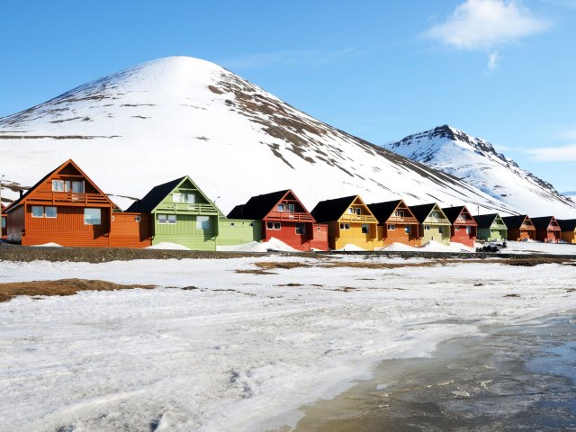 Row of homes painted in bright colors with snowy hill in background in Longyearbyen, Norway