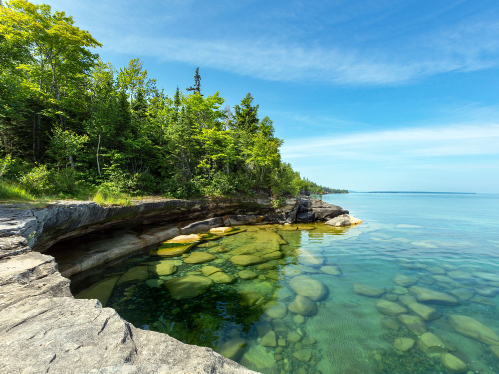 Translucent waters hugging forested shoreline of Lake Superior