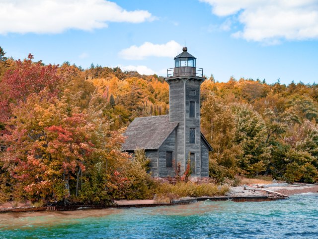 Wooden lighthouse on Lake Superior coast surrounded by autumn-colored trees