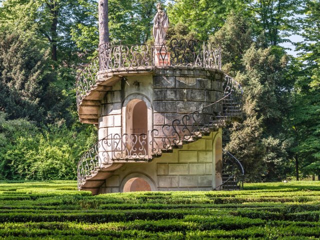 Stairs winding up tower topped by statue at Villa Pisani Labyrinth in Italy