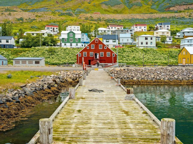 Dock leading towards colorful hillside buildings in Siglufjörður, Iceland