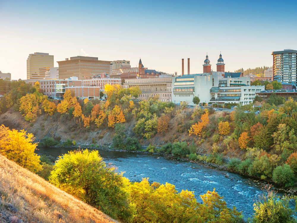 A picture of the city of Spokane perched on a small bank overlooking a rushing river