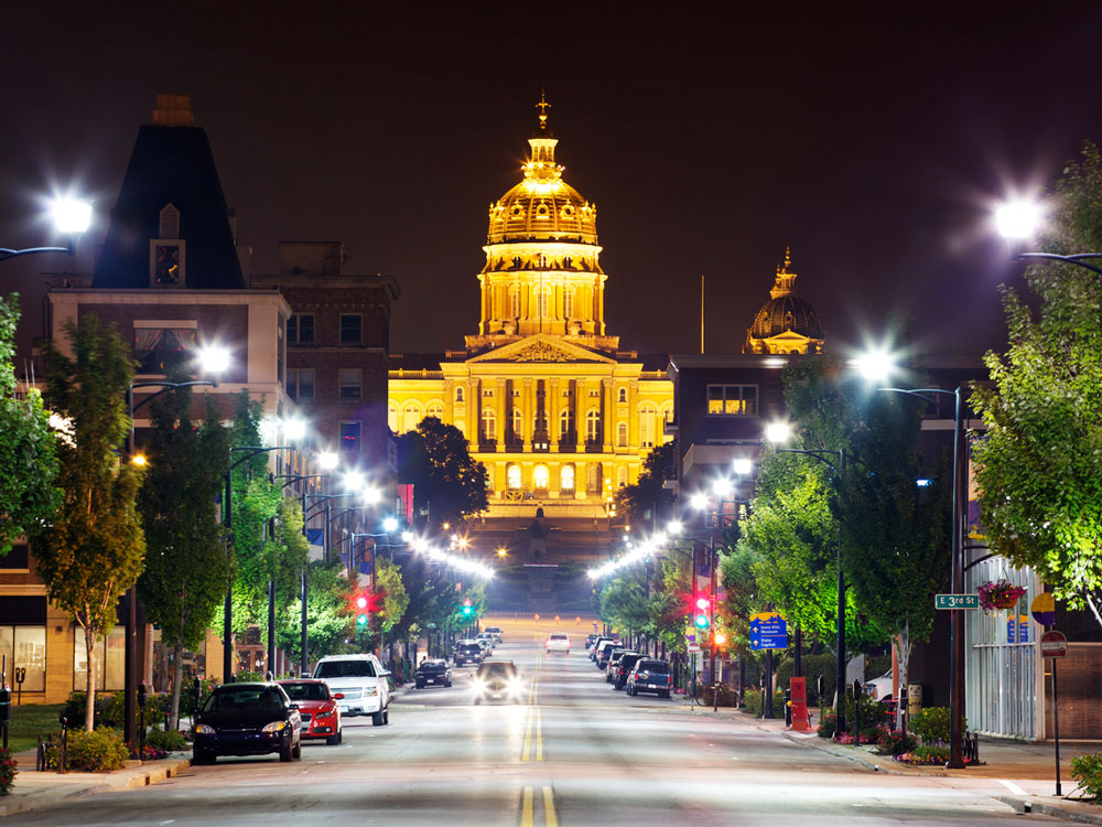 A picture of the Des Moines state capitol building illuminated with lights at night