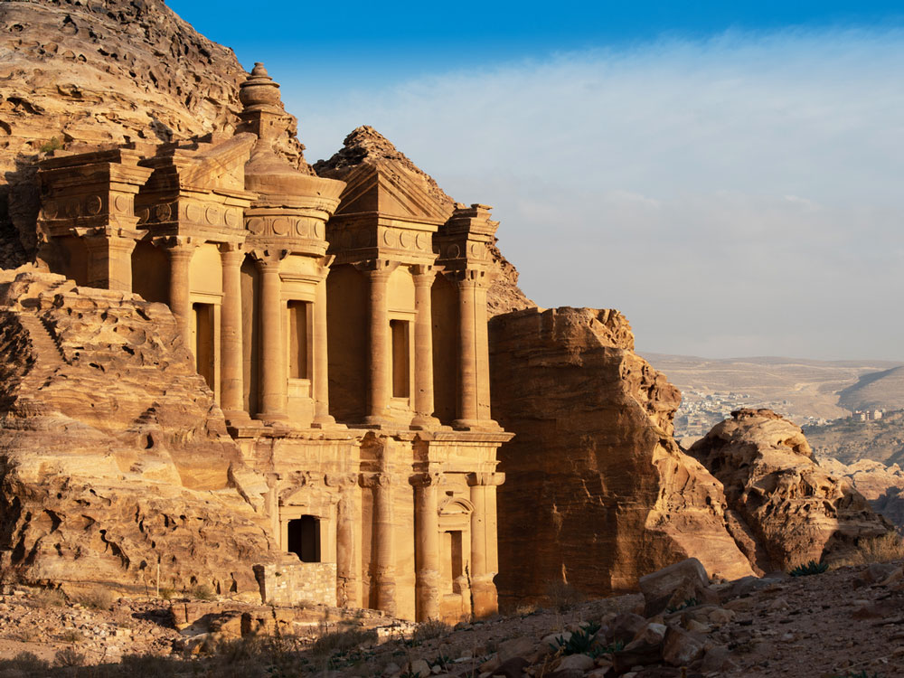 Buildings carved out of rock overlooking desert in Petra, Jordan