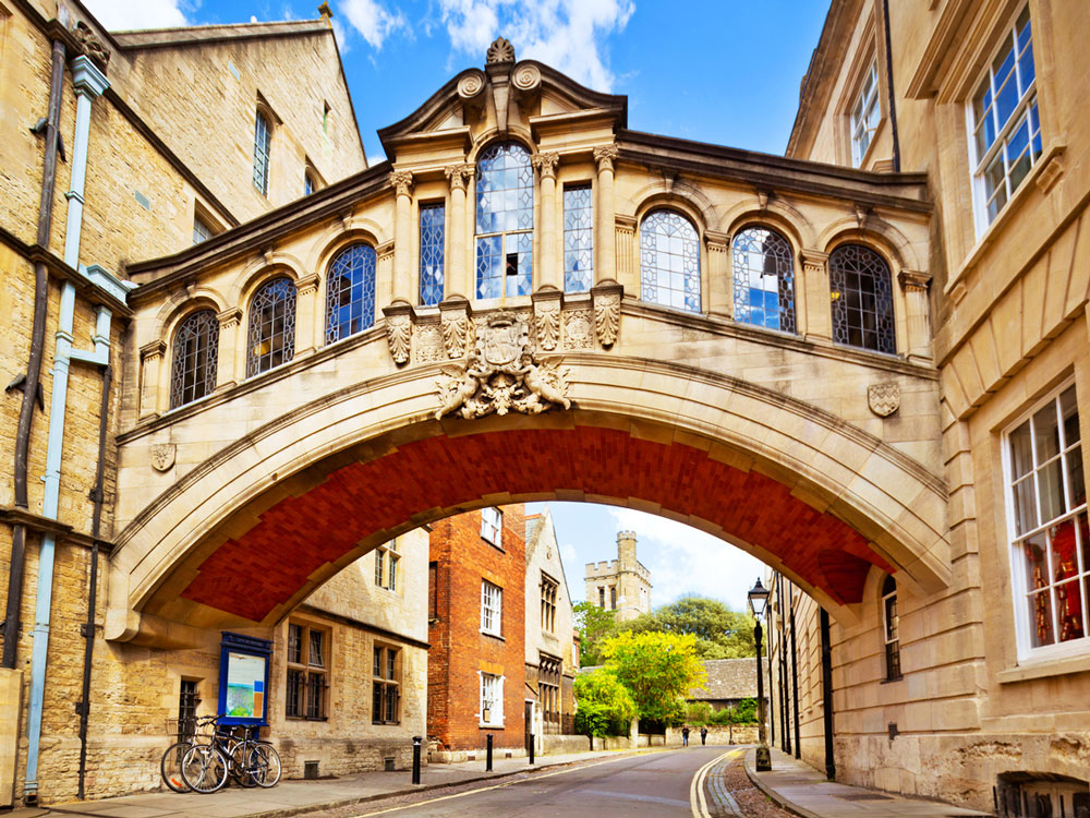 Arched stone bridge between buildings with stained glass windows in Oxford, England