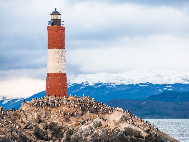 Penguin colony and red-and-white lighthouse on small island in Ushuaia, Argentina