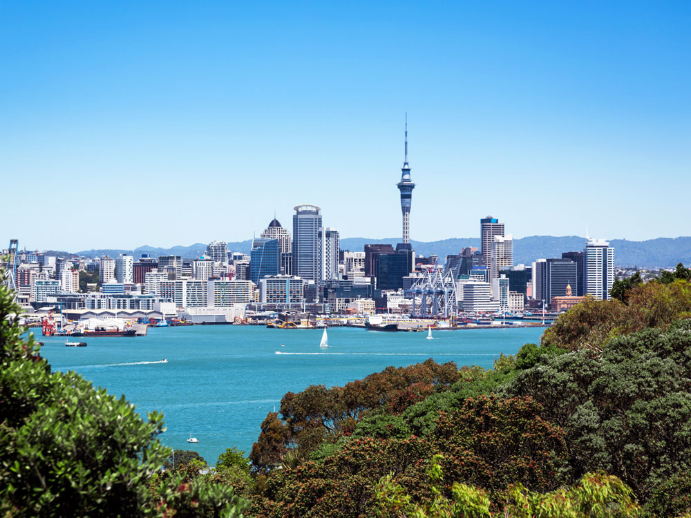 View of Auckland, New Zealand skyline from tree-covered island across bay