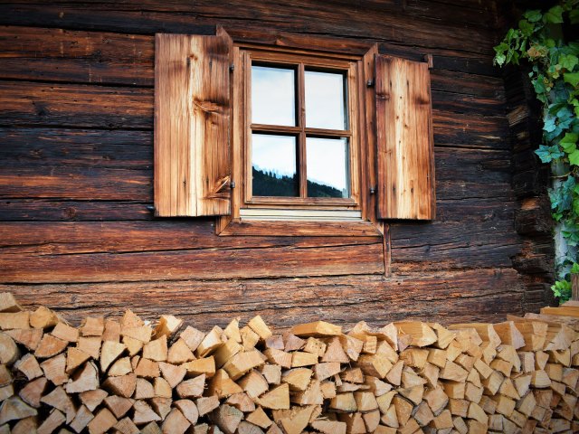Window of log cabin with firewood stacked below