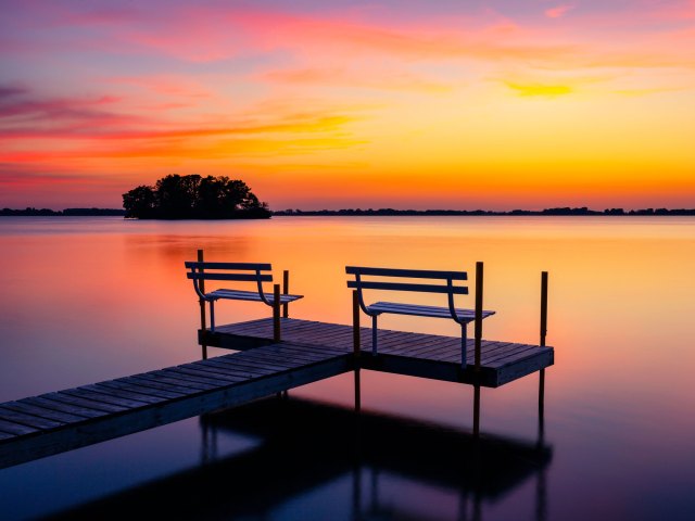 Empty benches on dock overlooking Wisconsin lake at sunset
