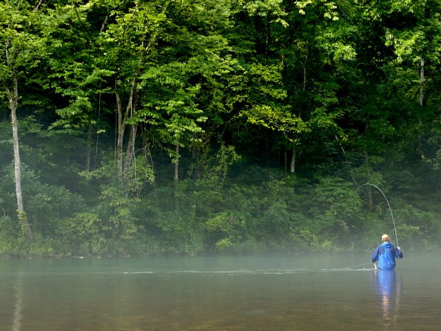 Person fly-fishing in river in Missouri
