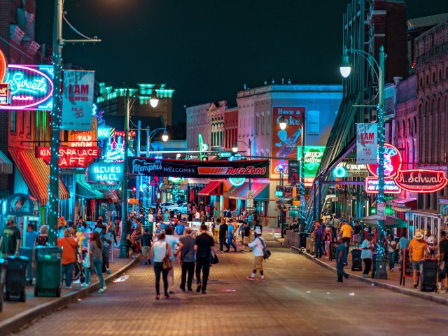 People walking along Beale Street lit by neon signs at night