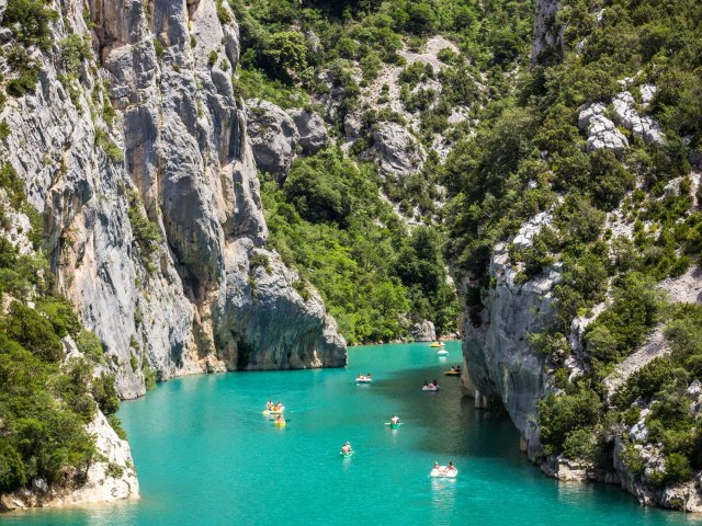 Boats in the turquoise waters flanked by tall limestone cliffs of France's Verdon Gorge