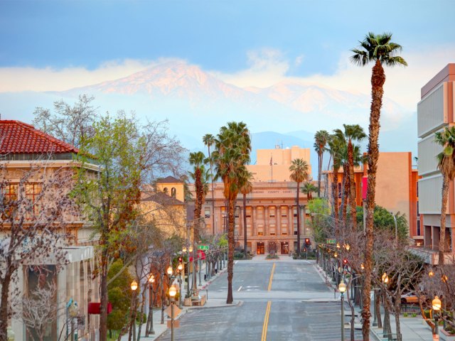 Palm tree-lined street in downtown San Bernardino, California, with mountains in background