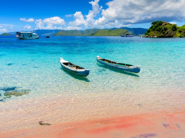 Boats moored off sandy beach in translucent waters of Komodo National Park in Indonesia
