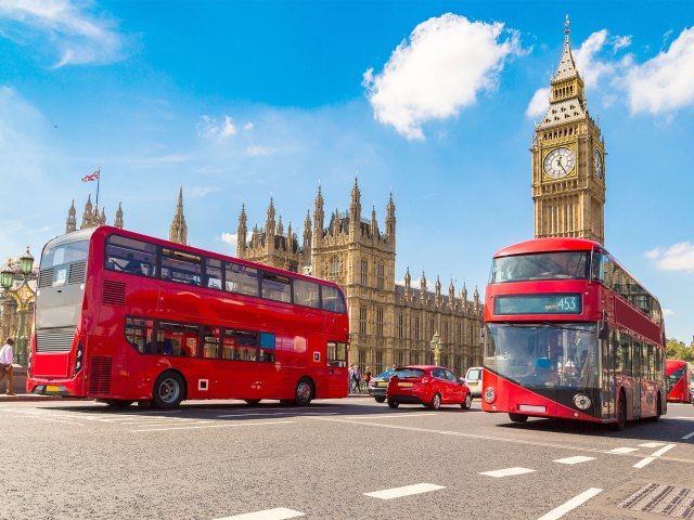 Iconic double-decker red busses in front of Big Ben in London, England