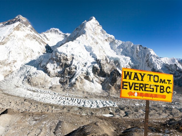Yellow sign indicating way to Mount Everest with snowy peak in background