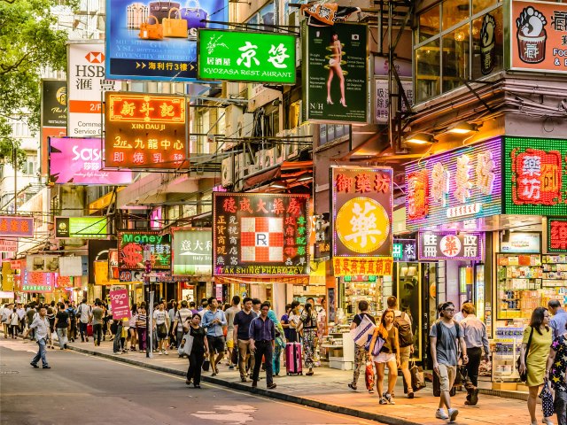 Street lined with storefronts crowded with pedestrians in Hong Kong