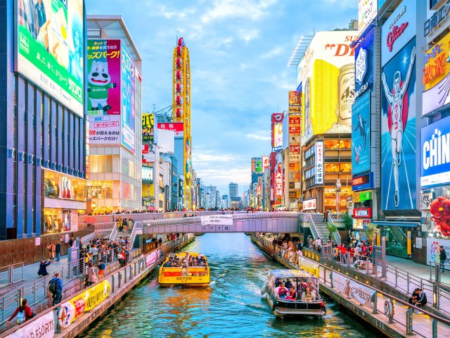 Boats on canal lined with neon signs in Osaka, Japan
