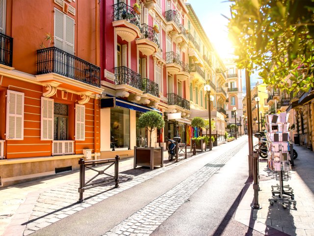 Sun shining through narrow street lined with homes in Monaco