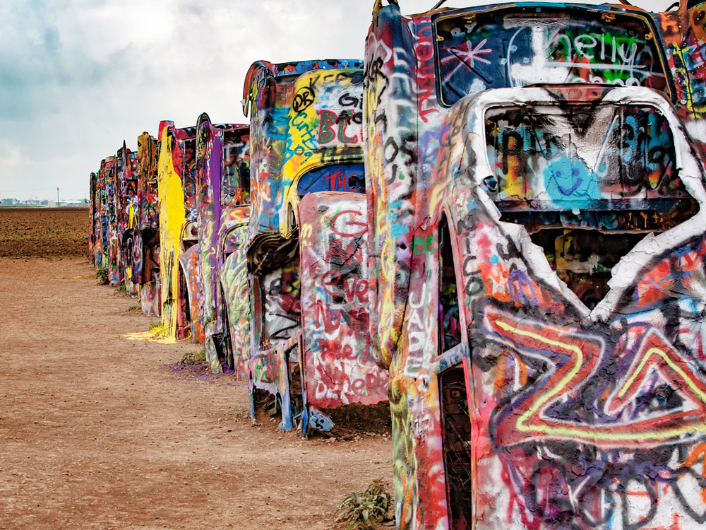 Graffiti-covered cars partially buried in sand at Cadillac Ranch in Texas
