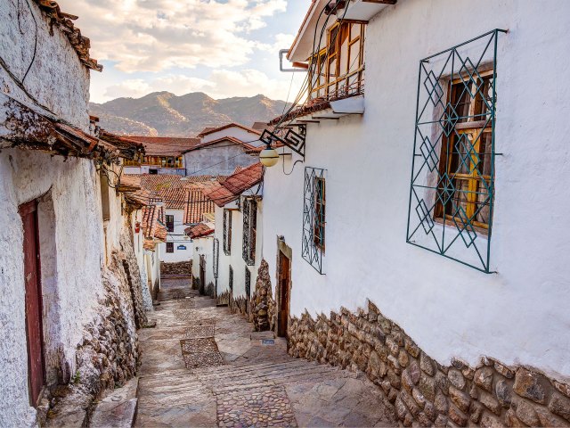 Narrow steps between whitewashed houses in Peru, with Andes mountains in distance