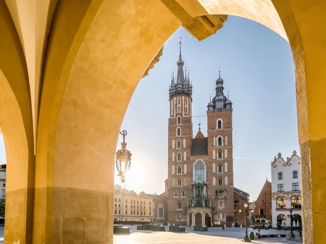 View of city square and church tower in Kraków, Poland, from beneath arches