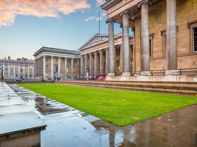Classical columned exterior of British Museum with grassy lawn in front