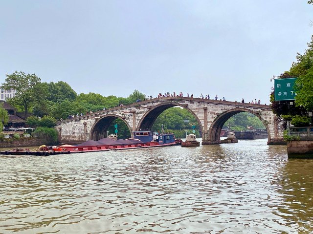 People standing on bridge as barge passes under on Jinghang Waterway (Grand Canal) in China