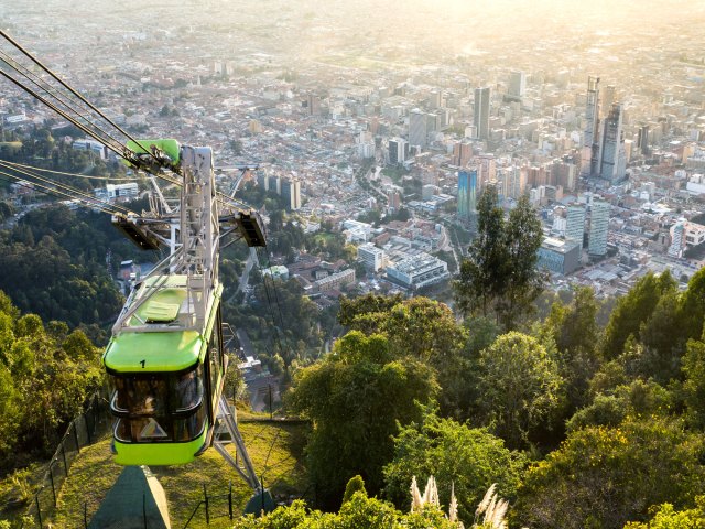 Aerial cable car traveling up mountainside with Bogotá skyline below