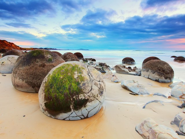 Moeraki Boulders resting on sandy shore in New Zealand