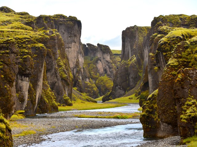 River flowing between verdant walls of Fjaðrárgljúfur Canyon in Iceland