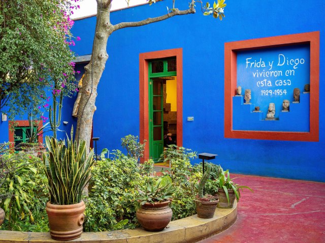 Lush courtyard with cobalt blue walls at Frida Kahlo Museum in Mexico City