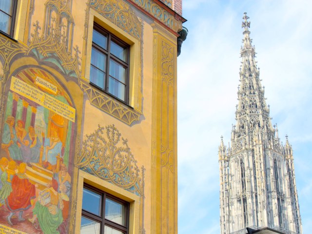 Yellow building with mural and steeple of Ulm Minster in Germany