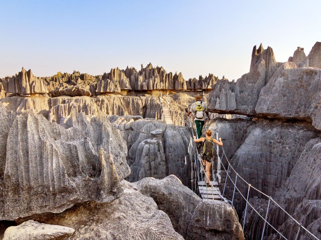 Person crossing bridge over narrow gap in rocks of Tsingy de Bemaraha Strict Nature Reserve in Madagascar